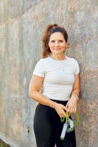 Precilla Barness with her hair on a ponytail, wearing a white gym-shirt and black leggings, holding a gree jump rope.